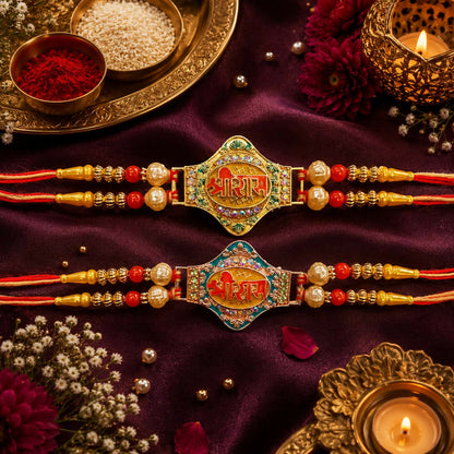 Two matching gold and pearl Rakhis with red and orange threads, one with a green center, the other blue, on a dark purple