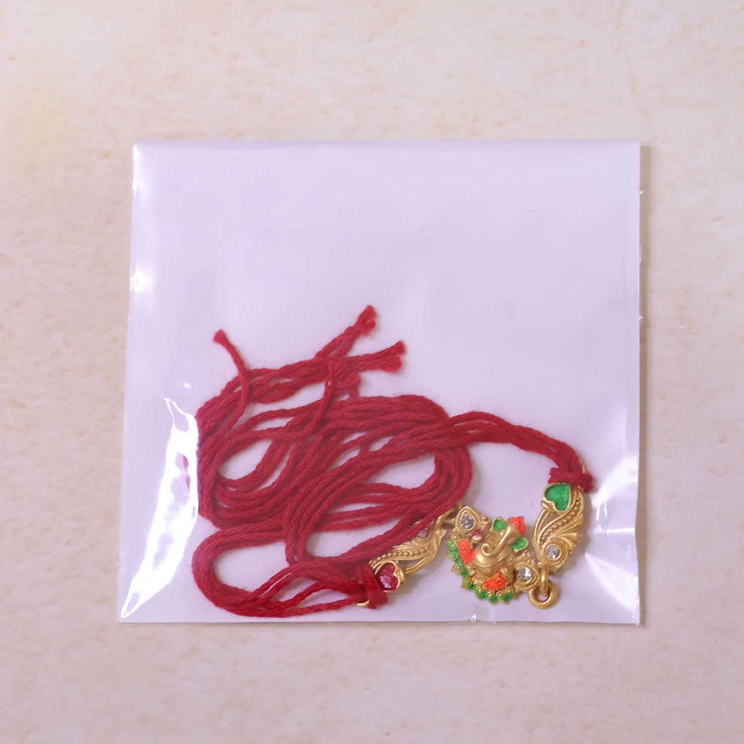 Gold-Toned Lord Ganesha Rakhi with Orange-Green Enamel, Crystal Accents & Red Thread