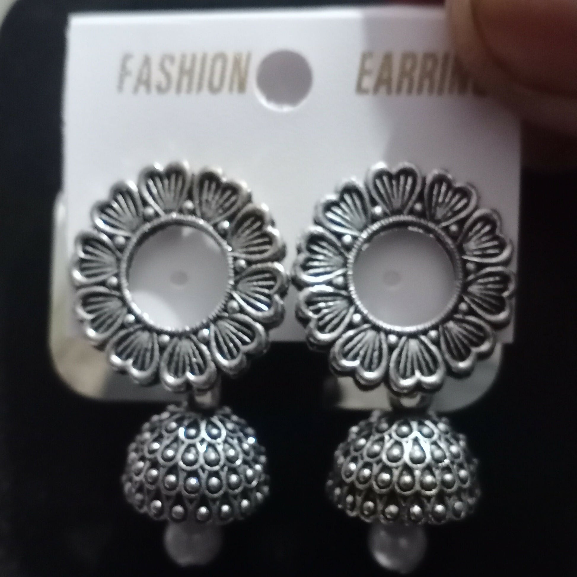 Detailed view of oxidized silver jhumka earrings highlighting floral motifs