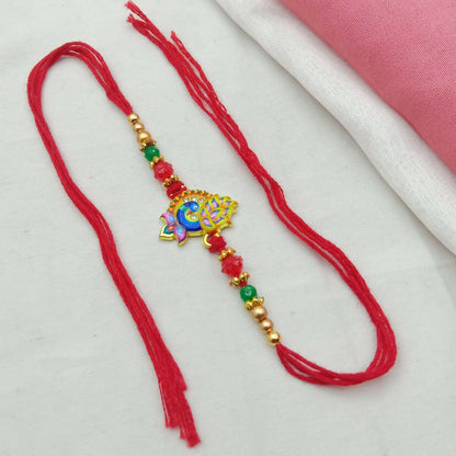 A golden-plated peacock enamel design with crystal stones and beaded thread is laid flat on a white and pink fabric