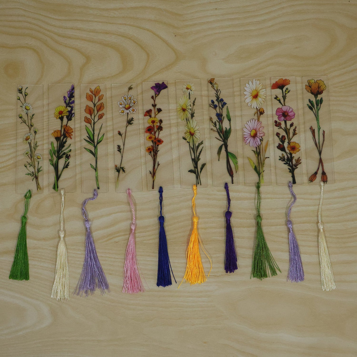 Transparent floral bookmark with a red flower and a yellow tassel, lying on a book with open pages
