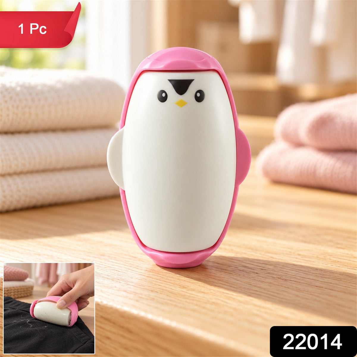The pink penguin lint roller on a wooden surface, with a small inset showing it in use on black fabric.
