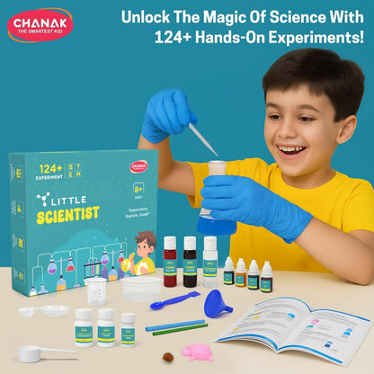 A child wearing blue gloves smiles while using a dropper with a blue liquid in a flask, with the kit contents and box