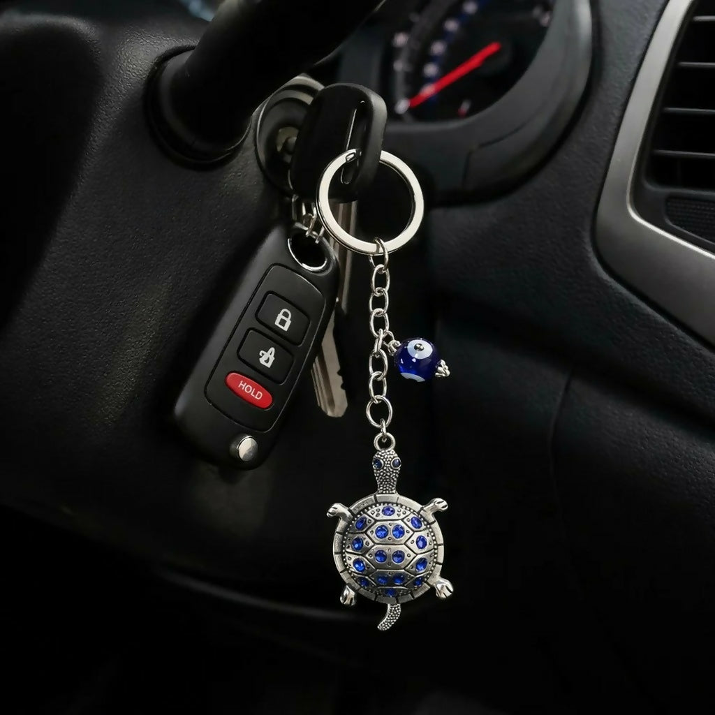 Turtle keychain with evil eye charm on white background
