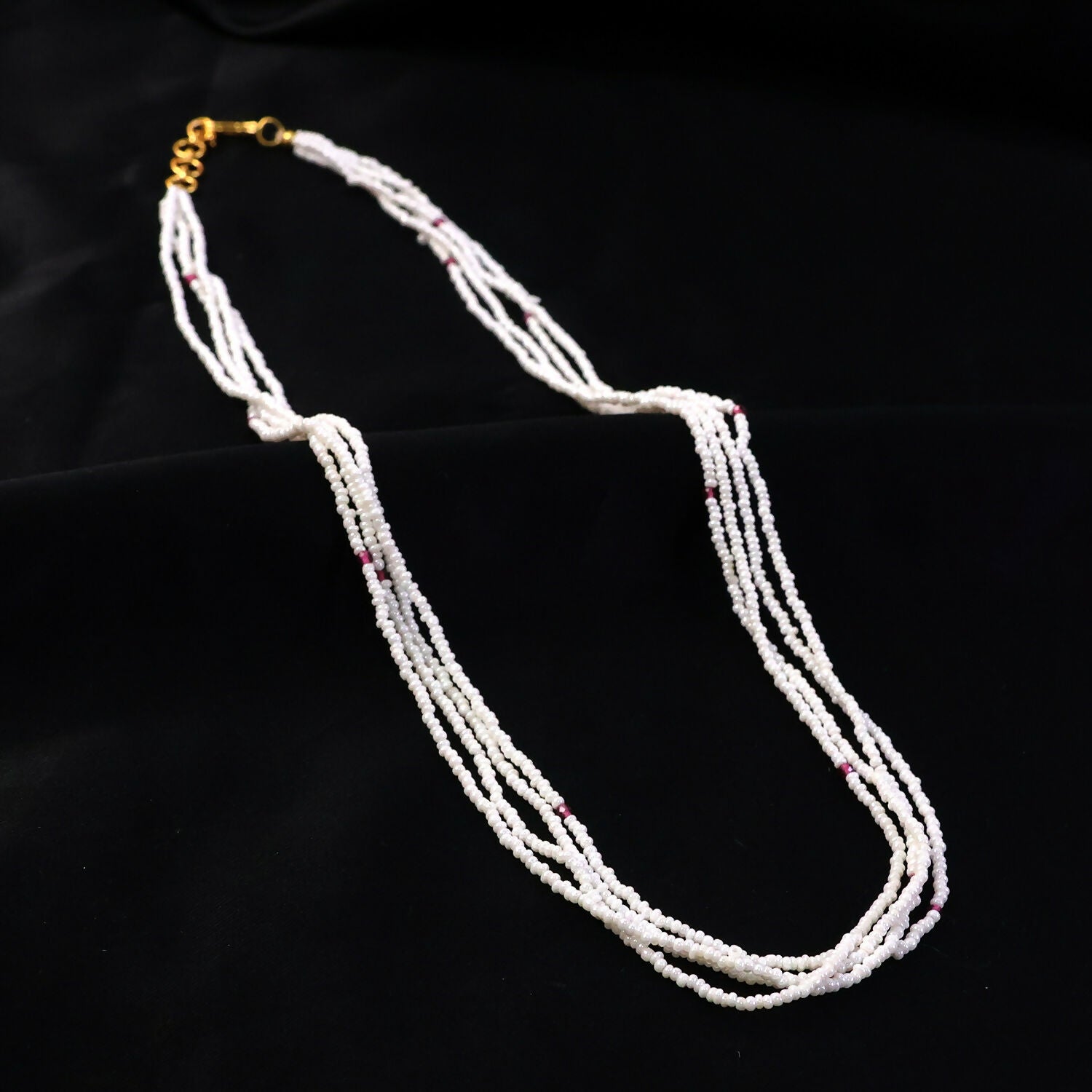 Detailed shot of pink accent beads on a layered pearl mala necklace