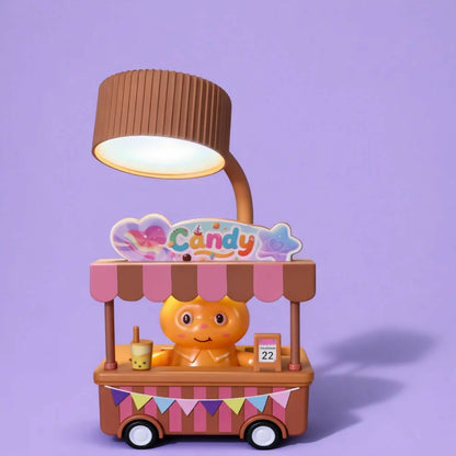 A brown and pink candy cart desk lamp with a glowing light, on a solid light purple background.