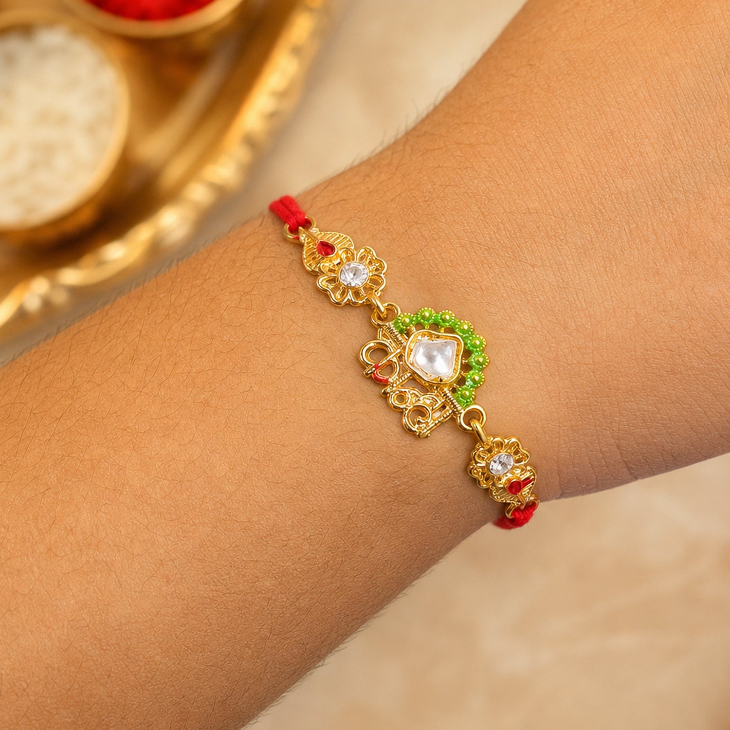 Gold-Toned Kanha Rakhi with Kundan-Style Stone, Green Enamel, Crystal Accents & Red Thread