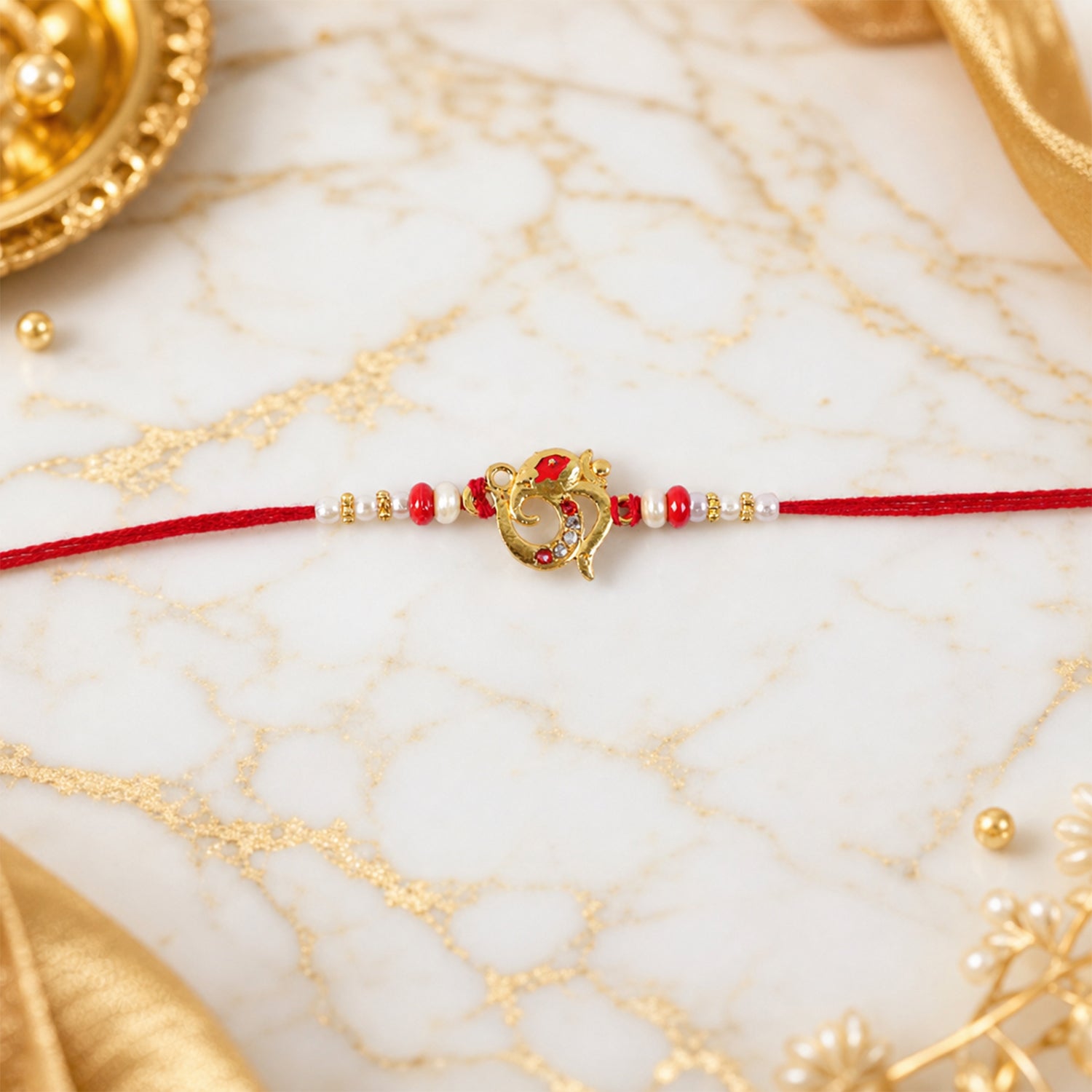Golden Om Rakhi with Red Beads and Pearl Dotted Thread