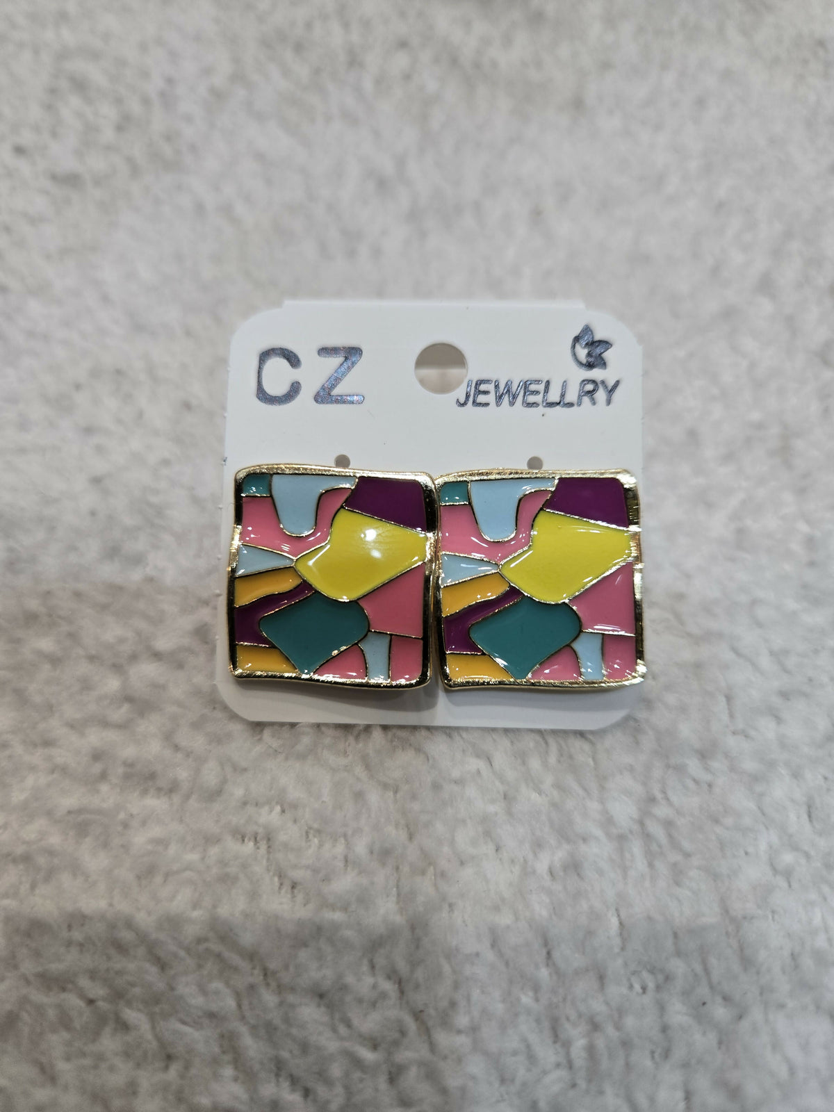 Two multicolour abstract square stud earrings are presented on a white card with