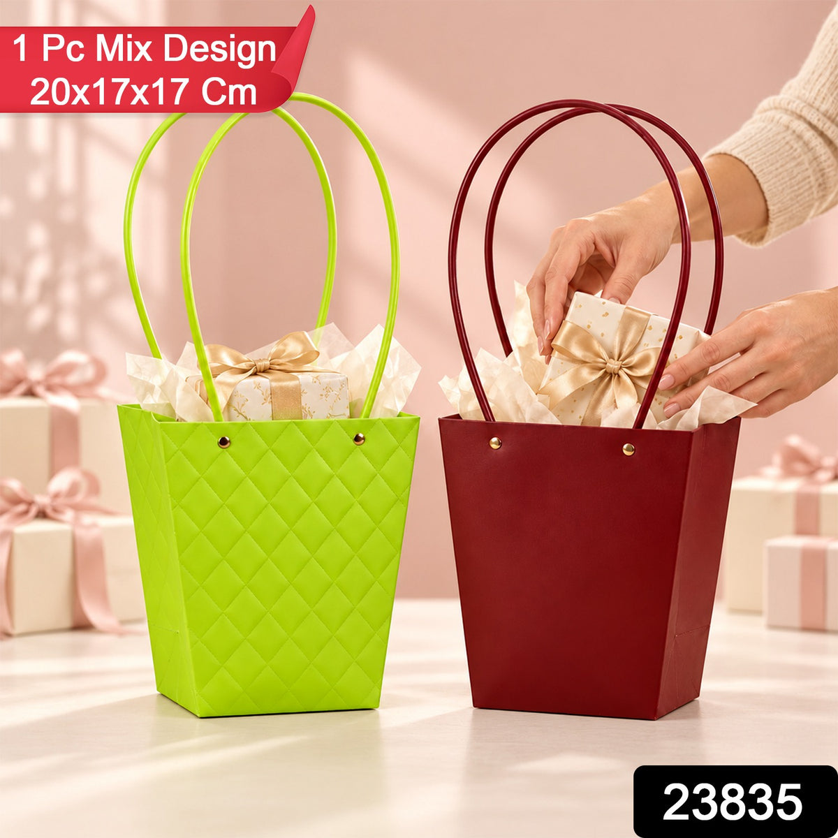 A person places a small golden wrapped present into a red tapered bag next to a lime green bag, both containing tissue