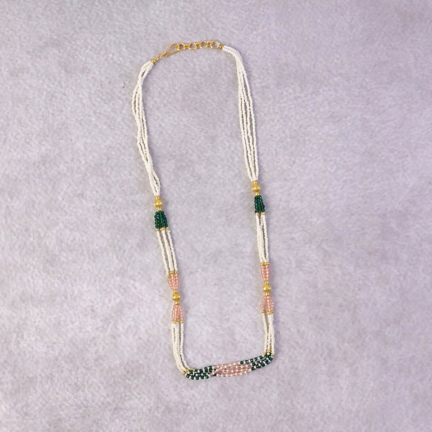 Side view of traditional beaded mala necklace with green and peach accents