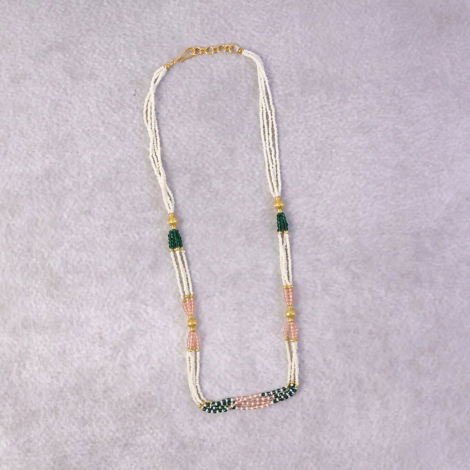 Side view of traditional beaded mala necklace with green and peach accents