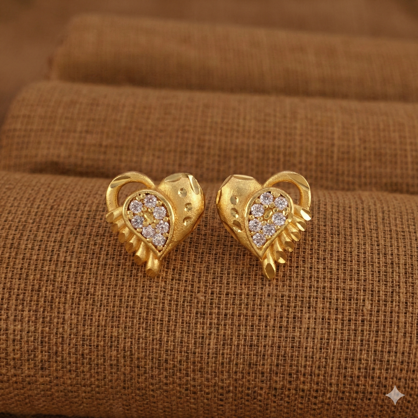 Elegant gold-plated heart-shaped stud earrings showing hammered texture and crystal detailing