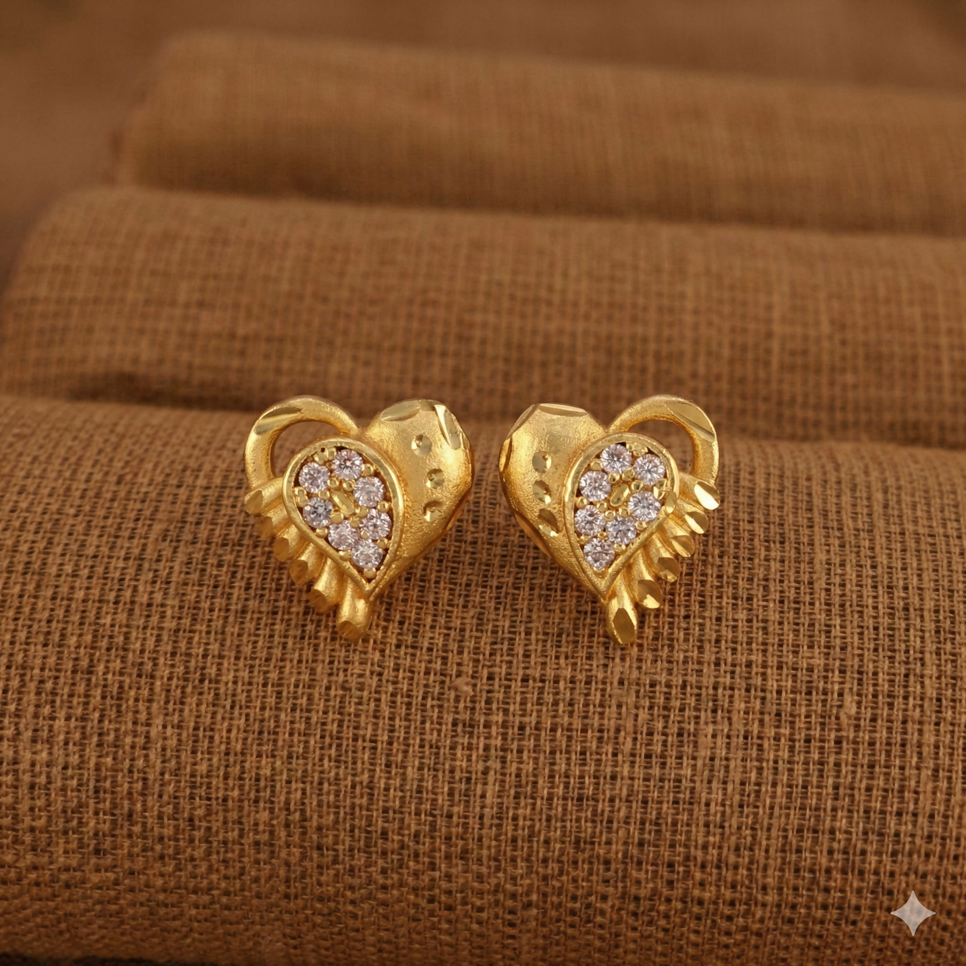 Elegant gold-plated heart-shaped stud earrings showing hammered texture and crystal detailing