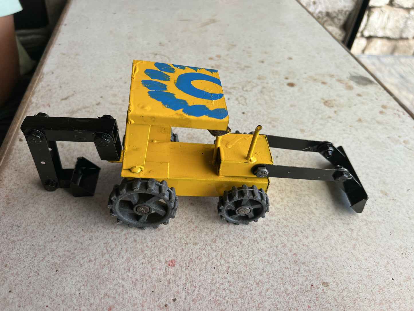 Handmade metal JCB toy displayed on rustic surface