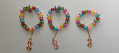 Three colorful beaded bracelets with various charms are laid out side-by-side on a plain light grey surface.