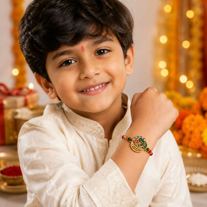 A young boy in a cream kurta smiles while wearing a colorful peacock and Ganesha bracelet on his right wrist.