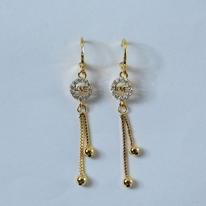 Close-up image showing crystal-encrusted “LOVE” charm in gold-finish earrings