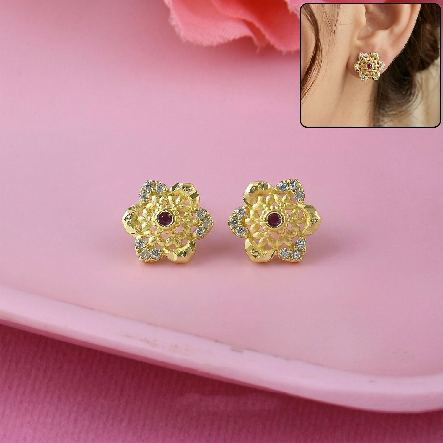 Close-up of gold stud earrings with floral design and sparkling center stone