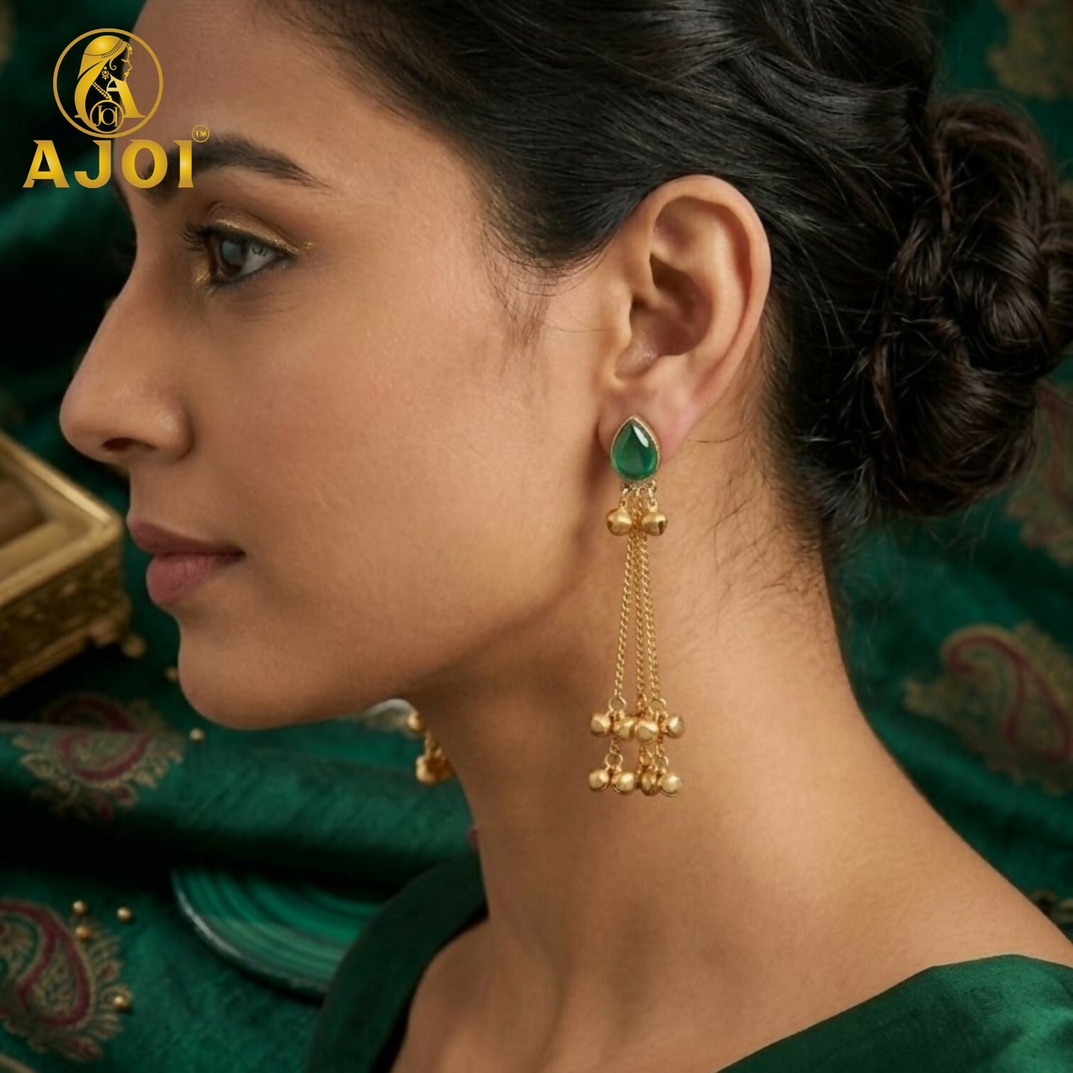 Pair of green stone gold plated drop earrings with ghungroo bells on display
