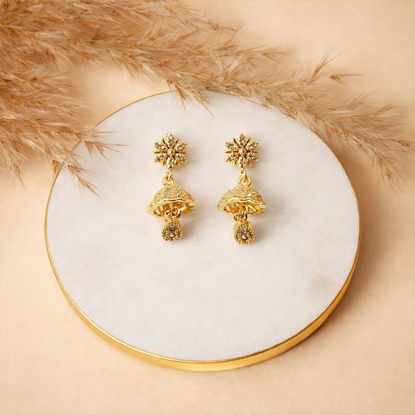 Pair of sunburst floral gold finish jhumka earrings showcasing detailed crystal embellishments