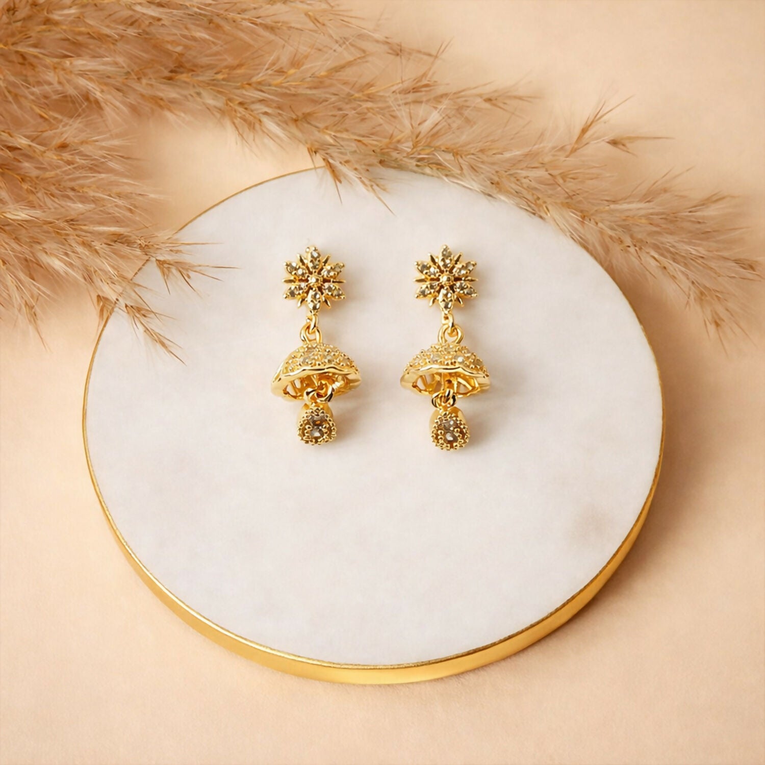 Pair of sunburst floral gold finish jhumka earrings showcasing detailed crystal embellishments