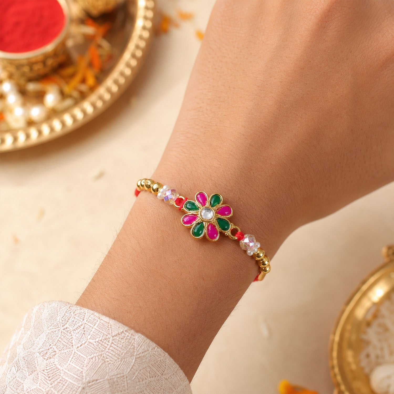 Radiant Floral Rakhi Adorned with Pink-Green Stones, Pearls and Gold-Tone Beads (5pcs)