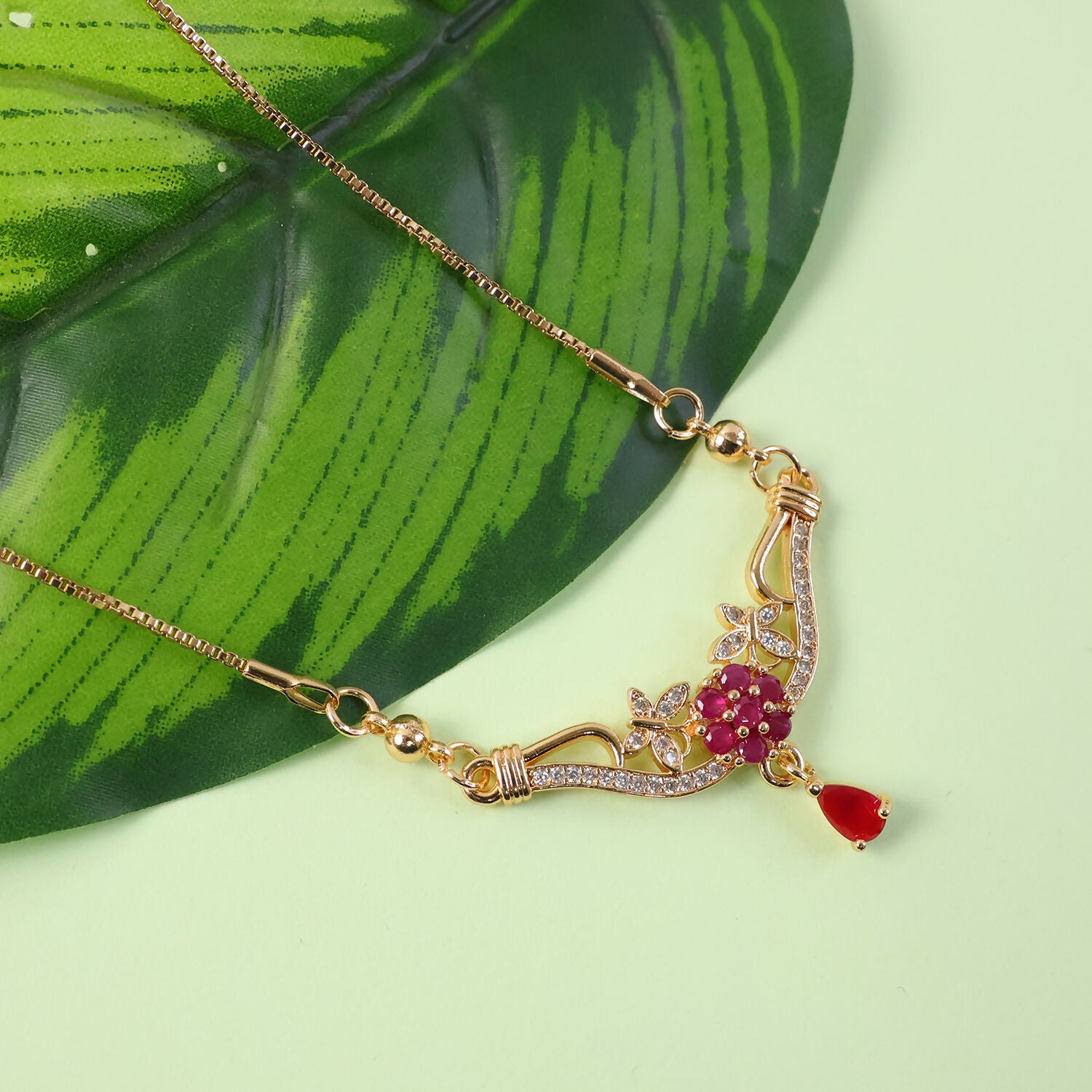 Gold floral necklace featuring intricate design and red stone drop pendant