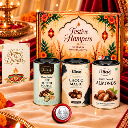 A decorative Diwali gift box with three tins of chocolates and nuts, plus a greeting card and silver coin.