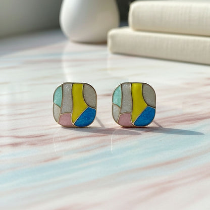 Close-up of multicolor enamel stud earrings with geometric pattern