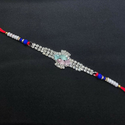 The crystal floral designer Rakhi, adorned with blue beads and red thread, is simply laid out on a plain black background.