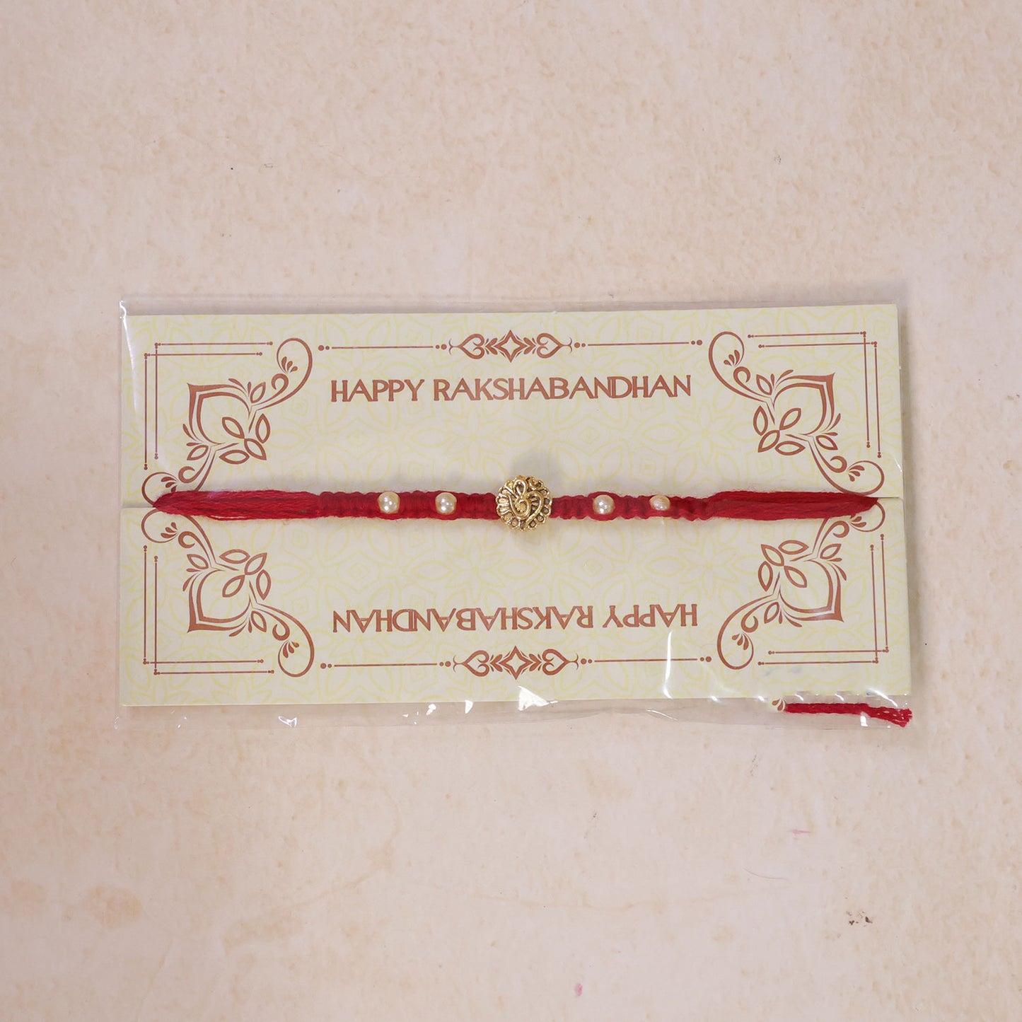 Red Braided Rakhi with Antique Gold Om Pendant and Lustrous Pearls