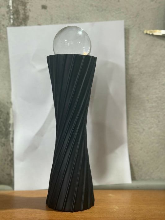 Elegant modern black twisted resin showpiece with glass ball on wooden surface