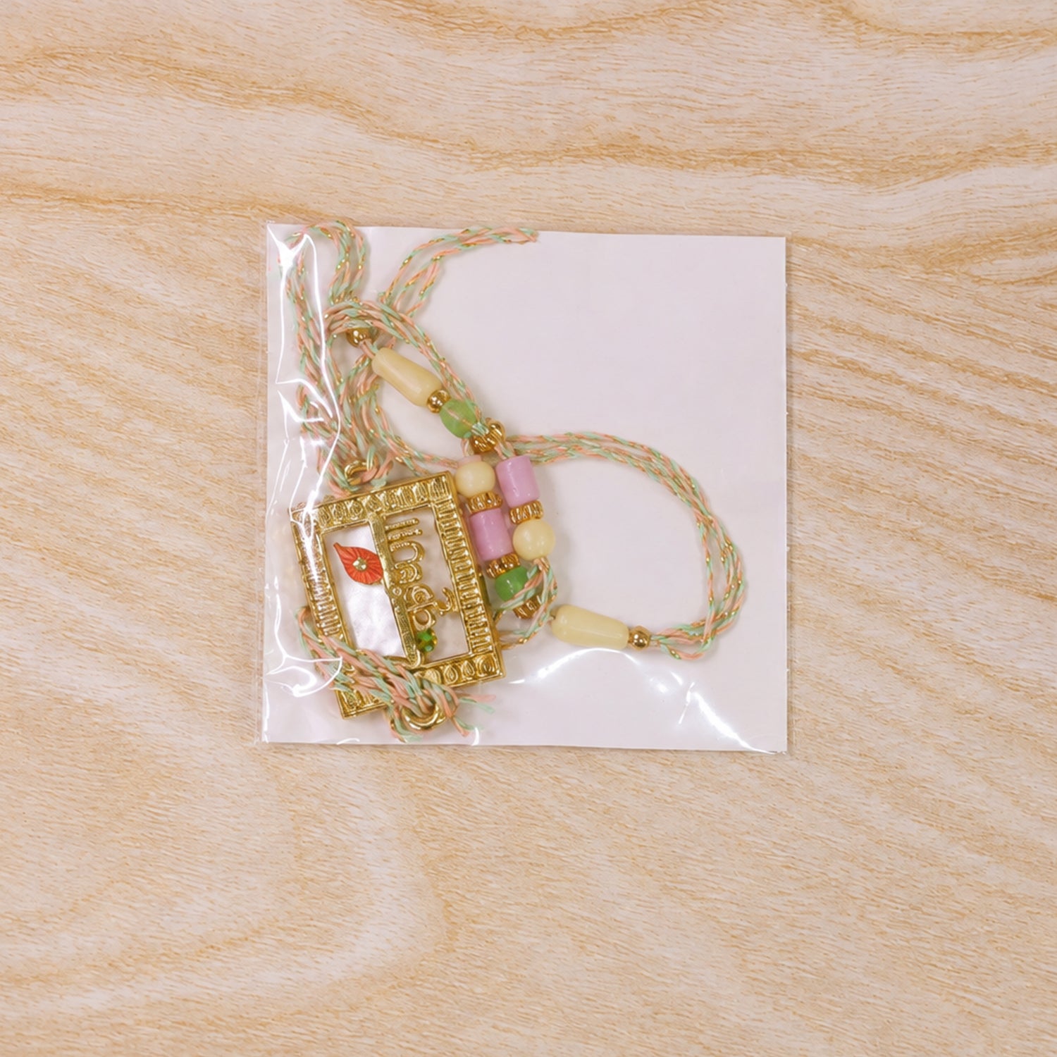Krishna Script Pendant Rakhi with Red Flower Accent