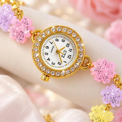 Close-up of the gold-toned watch face with a rhinestone-encrusted bezel and pastel glitter flower links.