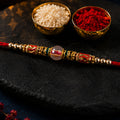 Golden Designer Rakhi with Red Green Stones for Raksha Bandhan