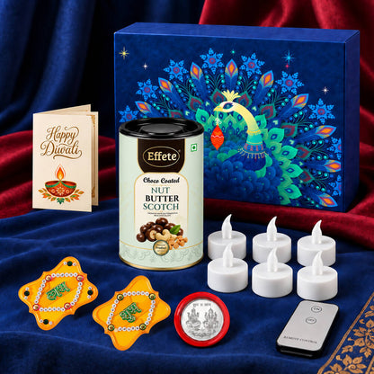 A dark blue box with a peacock design, a tin of nut butterscotch, a Diwali card, LED tealights, and two Shubh-Labh
