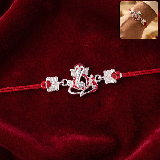 Elegant silver Ganesha rakhi for brother with red stone hearts, displayed on a white background.