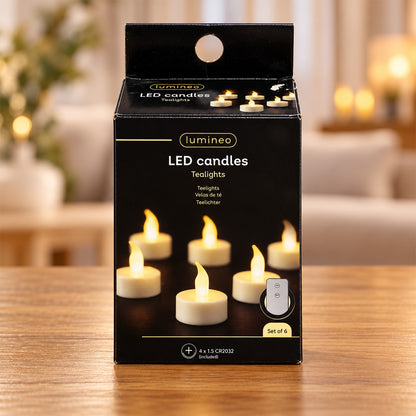 Six white LED tealights with flickering flames and a remote control in a black box on a wooden surface.