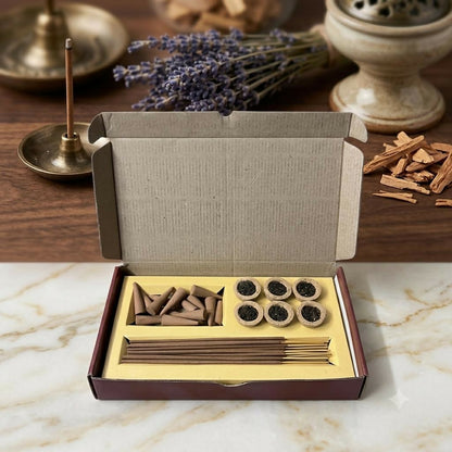 An open cardboard box containing incense cones, sambrani cups, and sticks on a marble surface with lavender in the