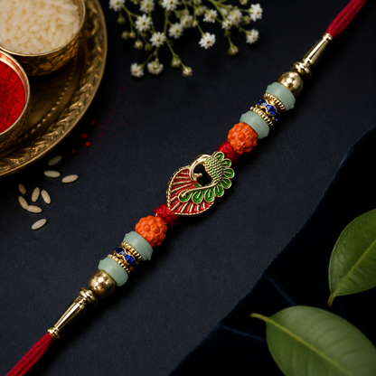 A red and gold bracelet with a peacock charm, orange and light green beads, and blue accents, surrounded by white flowers,