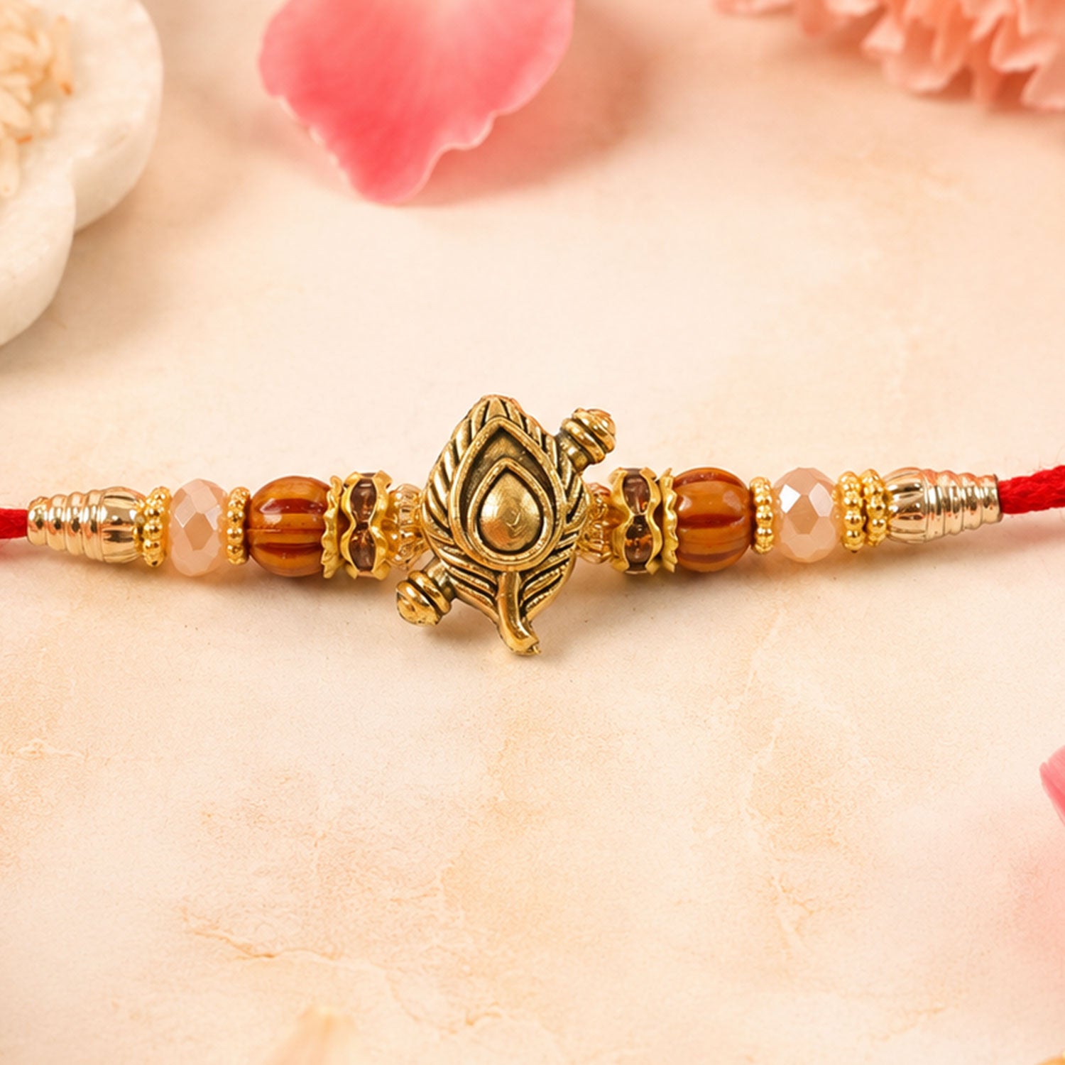 Peacock Paisley Golden Rakhi with Leaf Style Centre, Red Thread and Pearl Accents