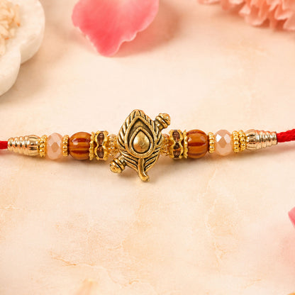 Peacock Paisley Golden Rakhi with Leaf Style Centre, Red Thread and Pearl Accents
