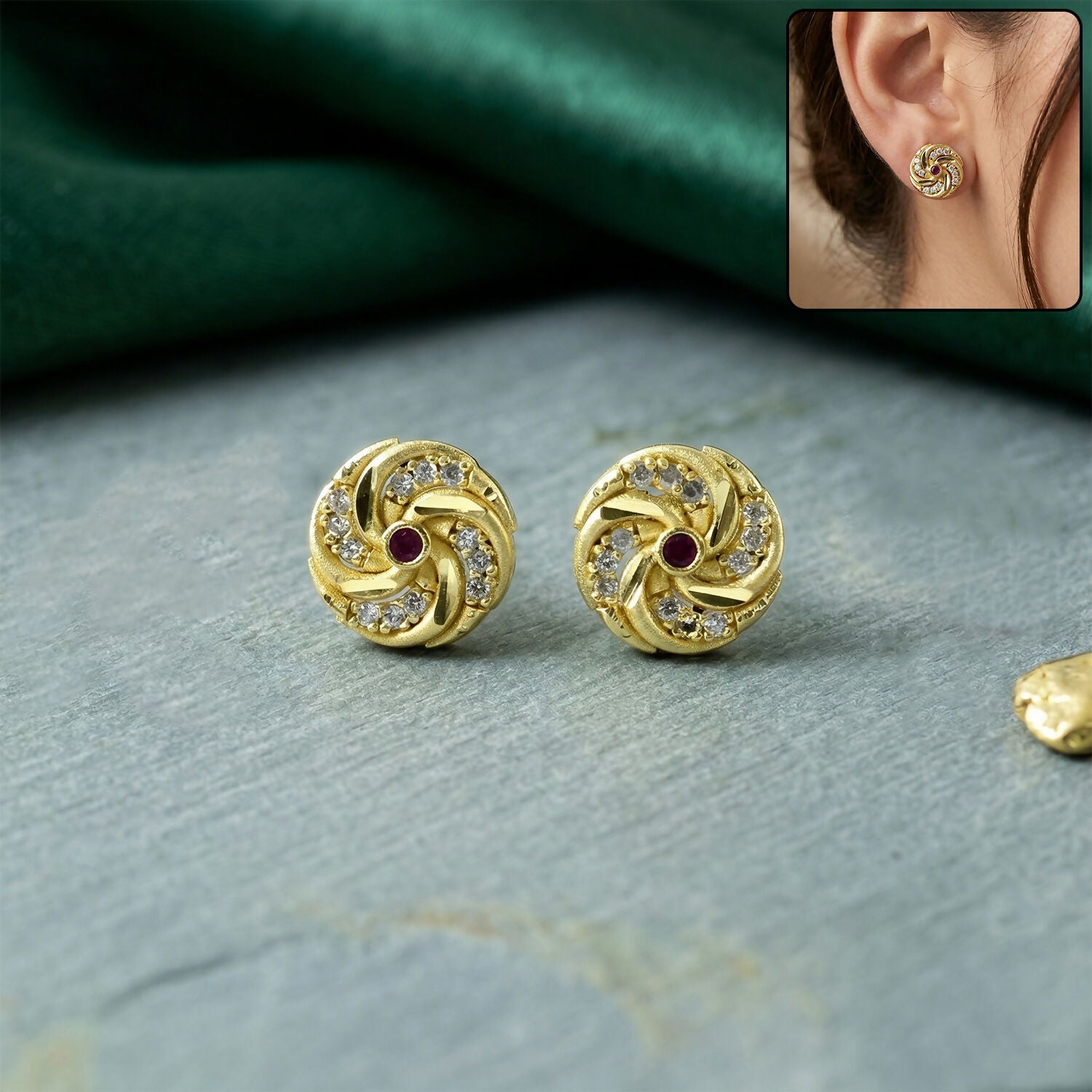 Gold stud earrings with spiral pattern and red stone detail