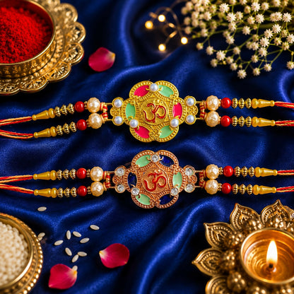 Two gold and rose gold Om bracelets with colorful enamel and pearls, surrounded by red beads, on a deep blue silk fabric.