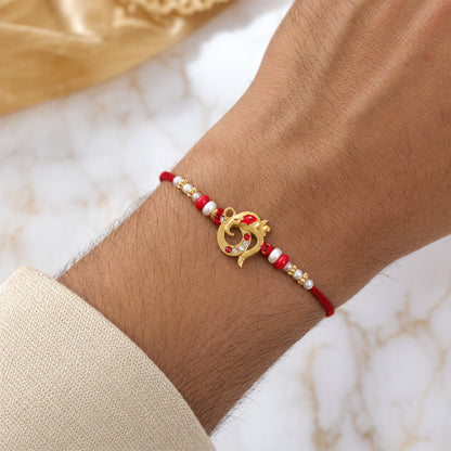 Golden Om Rakhi with Red Beads and Pearl Dotted Thread