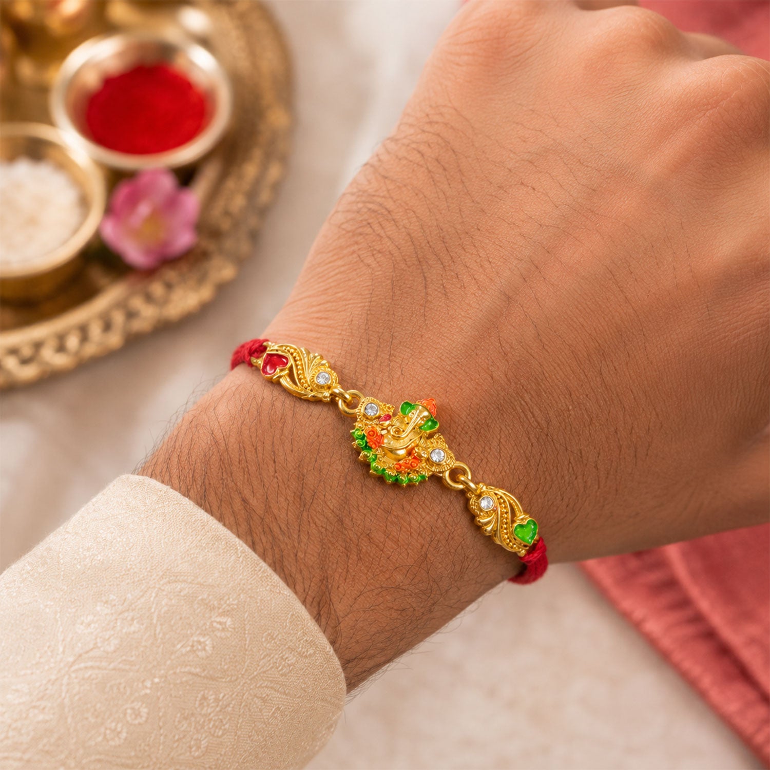 Gold-Toned Lord Ganesha Rakhi with Orange-Green Enamel, Crystal Accents & Red Thread