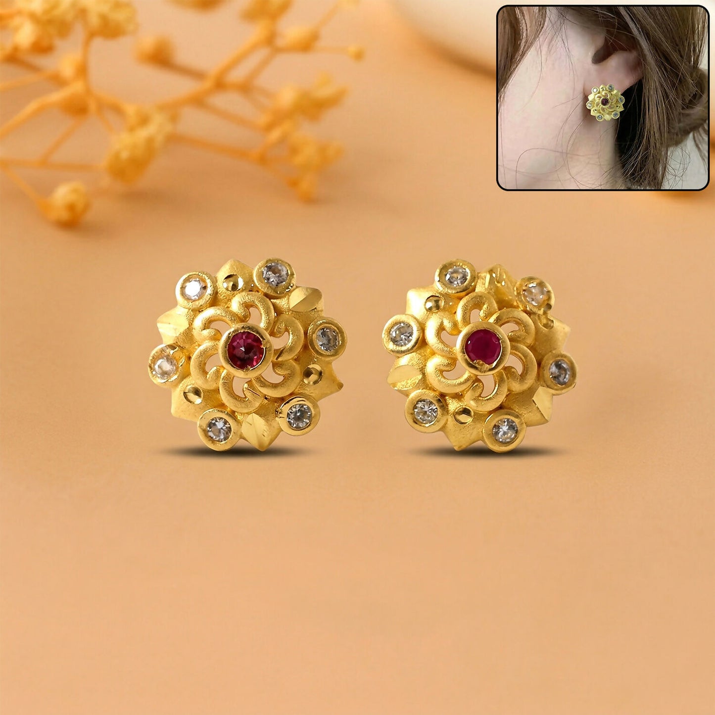 Close-up of gold stud earrings with floral design and sparkling stones