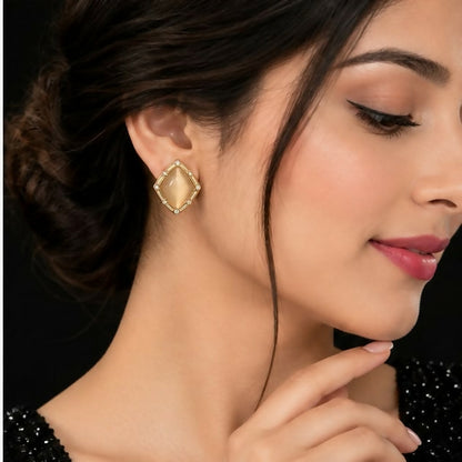 A woman models a single champagne geometric stud earring, showcasing its size and placement on her earlobe.
