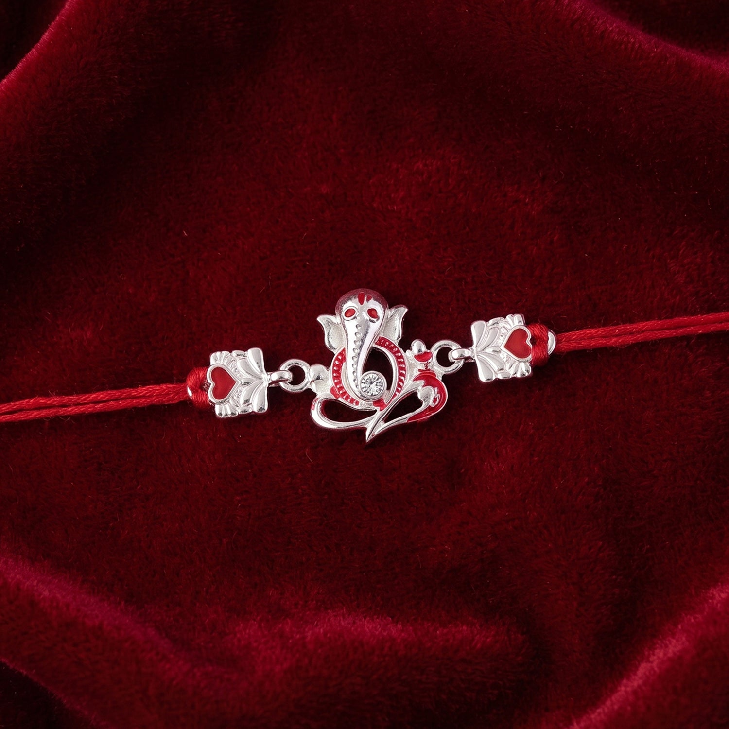 Silver Ganesha Rakhi with Red Stone Hearts and Deep Velvet Look